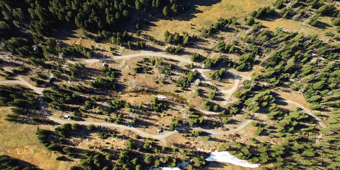Aerial view of a dirt road winding through timber