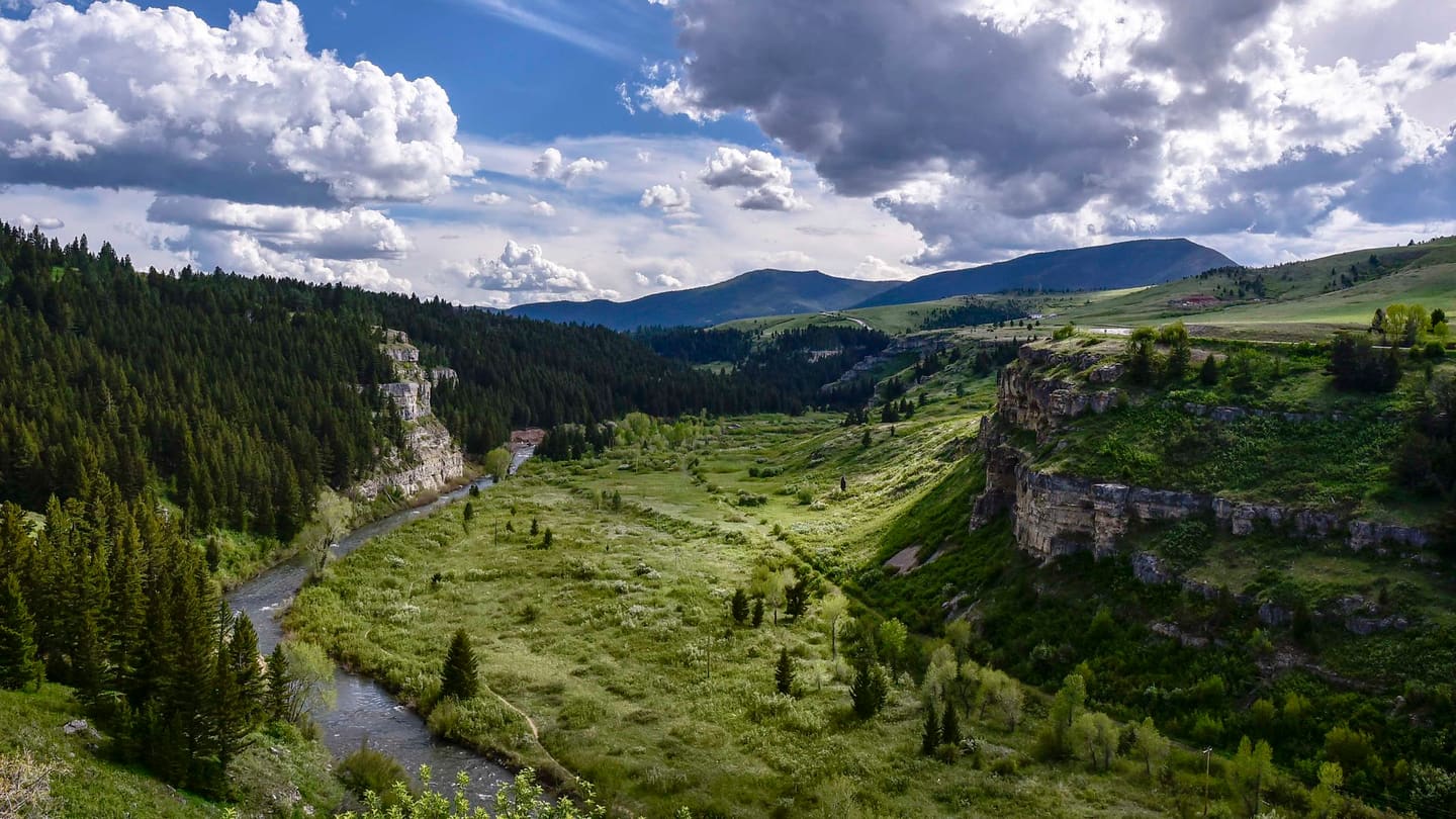 Belt Creek winding through a green canyon under cliffs in Sluice Boxes State Park